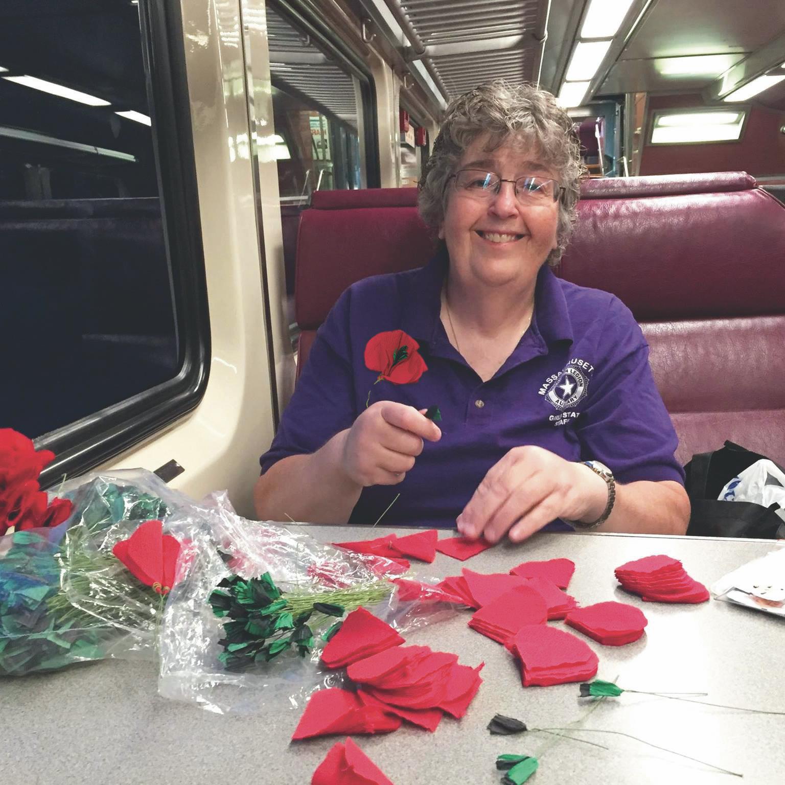 Wearing a poppy supports veterans | Pictured is Ann Fournier making the poppy flowers on the train.