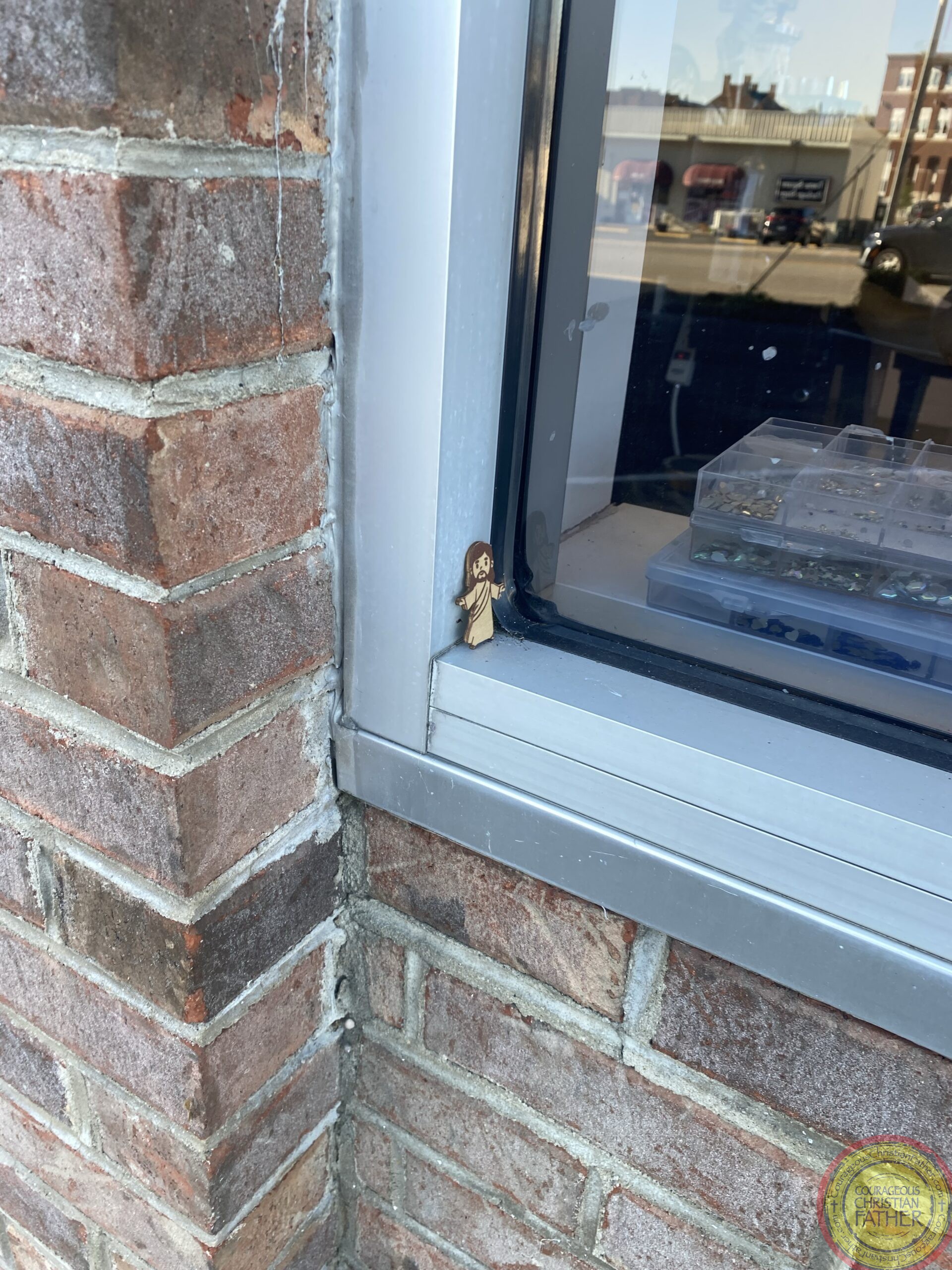 The wooden Little Jesus outside this business window. ​