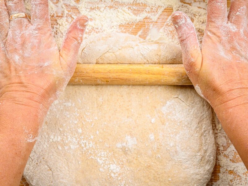 a person with their hands on a rolling dough